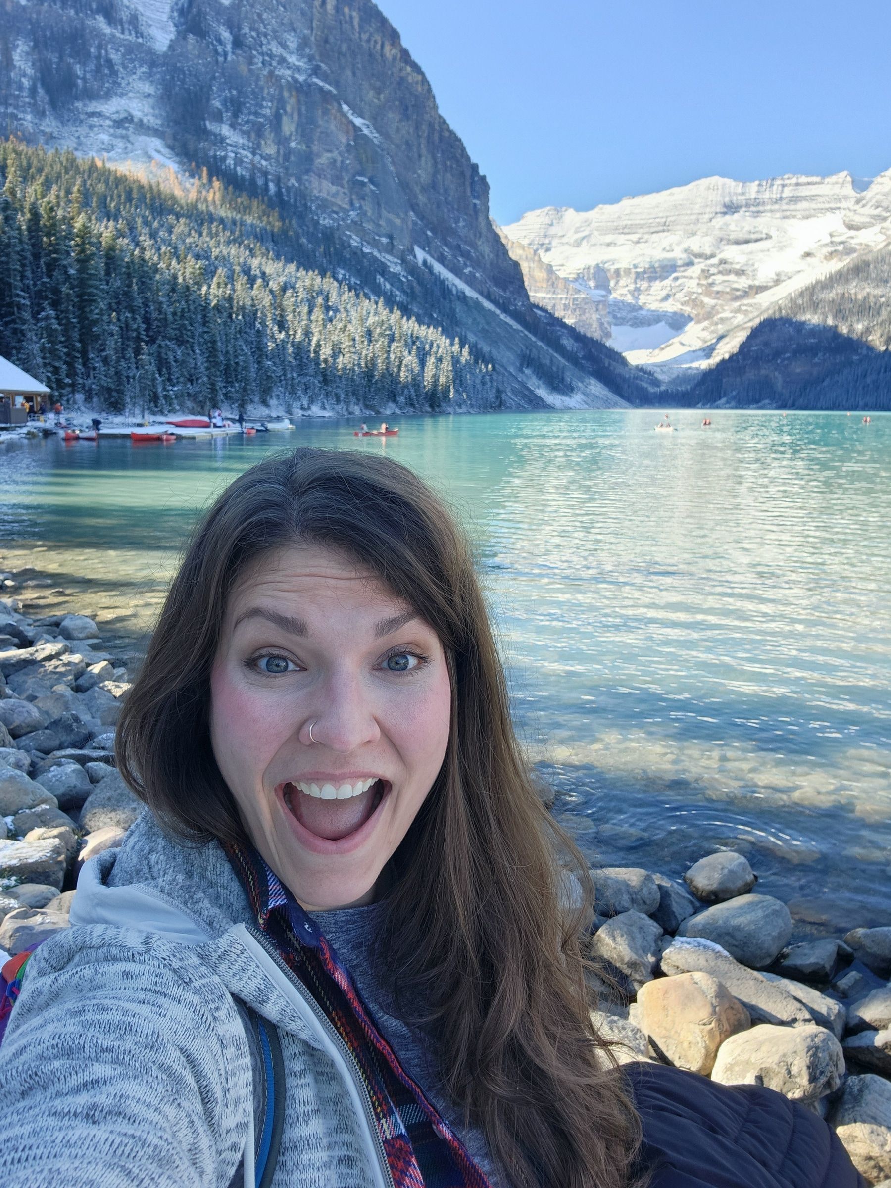 Leah smiling in front of a turquoise lake and snow-covered mountains